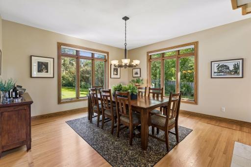 Expansive windows surround the dining room with natural light and wooded views.