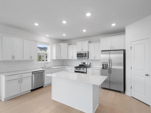 This stylish and multifunctional kitchen comes complete with brand-new stainless steel appliances, sleek quartz countertops and Shaker-style cabinetry.