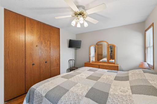 Second upper level bedroom with neutral tones and a ceiling fan.