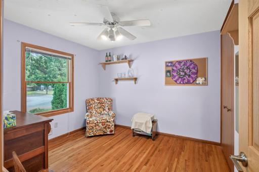 Upper-level bedroom with hardwood floors, natural light, and a ceiling fan.
