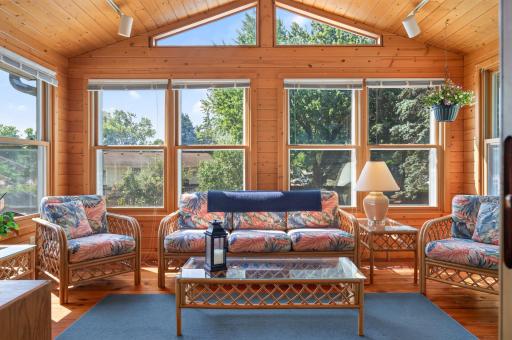 Three-season porch surrounded by windows with beautiful backyard views.