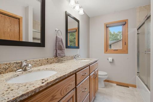 The beautiful main floor bathroom is nicely updated with double sinks, quartz countertops, and a tile shower with built in shelving.