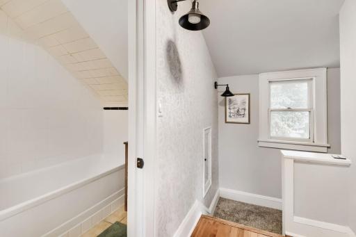 A quaint upstairs landing with charming wall sconces welcomes you to the second level, where two bedrooms and a full bathroom await.