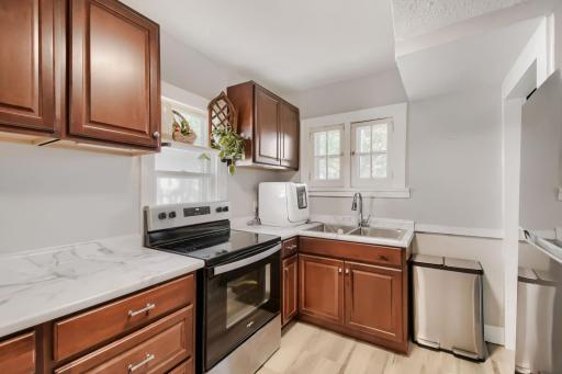 The kitchen offers stainless steel appliances, including an electric range and refrigerator, complemented by modern countertops and cabinetry. A countertop dishwasher is also included for added convenience.
