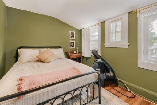 The primary bedroom features natural-toned flooring and a convenient window air conditioner for added comfort.