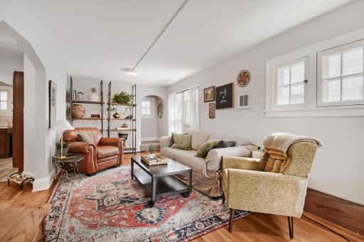 The spacious main-level living room showcases original hardwood floors, neutral tones, and beautiful natural light, creating a warm and inviting space with timeless character.