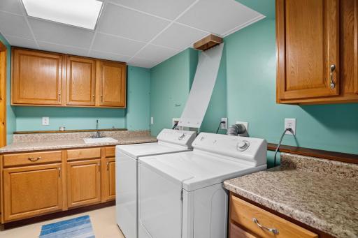 Generous laundry room featuring abundant cabinetry, counter space, a utility sink, and room for organization.