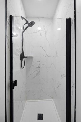 Private ensuite bathroom with tiled shower, glass enclosure, and modern black fixtures.