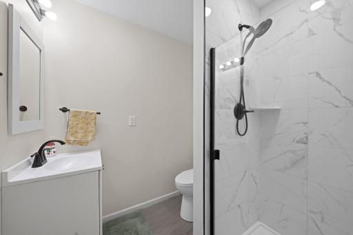Private ensuite bathroom with tiled shower, glass enclosure, and modern black fixtures.