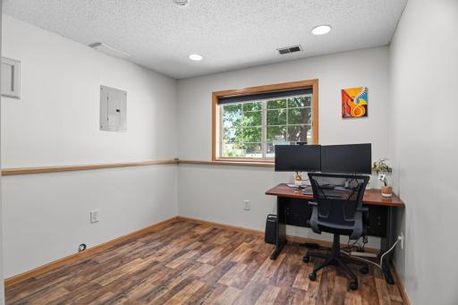 A bright lower-level office with a large window and plenty of space for working from home or studying.