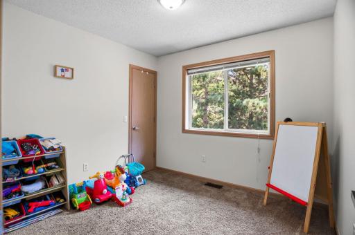 A bright upper-level 2nd bedroom with a large window, generous closet space, and flexible use as a bedroom, playroom, or office.