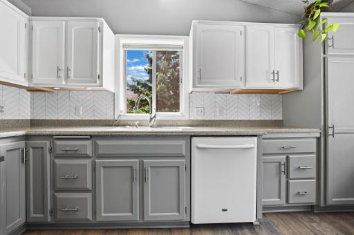 A bright, refreshed kitchen featuring two-tone cabinetry, ample counter space, and a stylish herringbone backsplash.