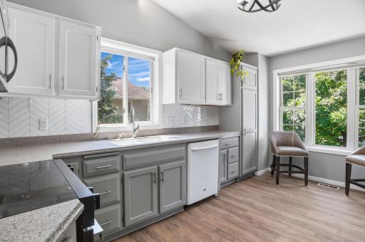 A bright, refreshed kitchen featuring two-tone cabinetry, ample counter space, and a stylish herringbone backsplash.