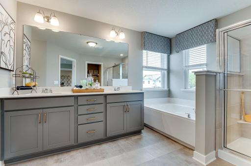 This lovely primary bath has a soaking tub, walk in shower with tile surround and two walk in closets. Photo of model, colors and finishes vary.