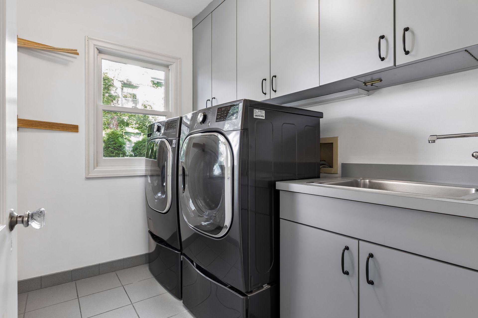 Main level laundry is located off of a back hall near the kitchen and secondary "back" staircase. A laundry chute delivers items to the cabinetry above the laundry sink.