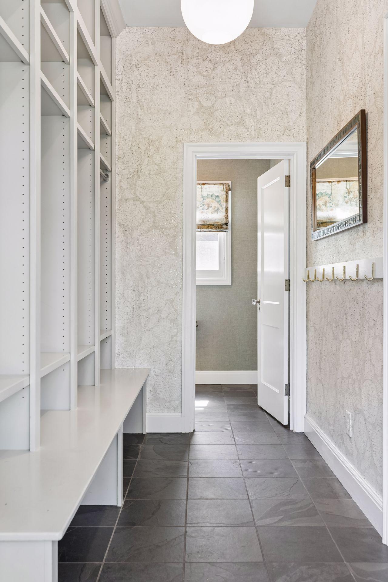 A perfectly appointed and spacious mudroom with tile floors and one of two main level powder rooms. The informal coat storage supplements a formal walk-in coat closet near the front entrance.