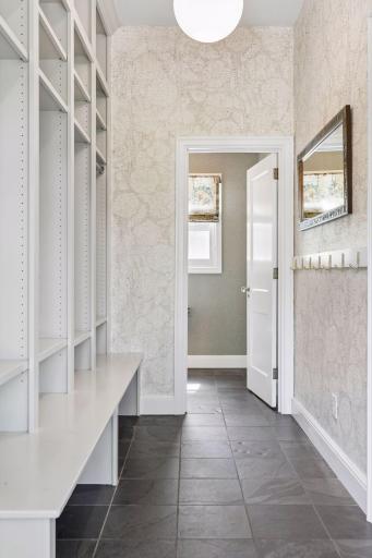 A perfectly appointed and spacious mudroom with tile floors and one of two main level powder rooms. The informal coat storage supplements a formal walk-in coat closet near the front entrance.