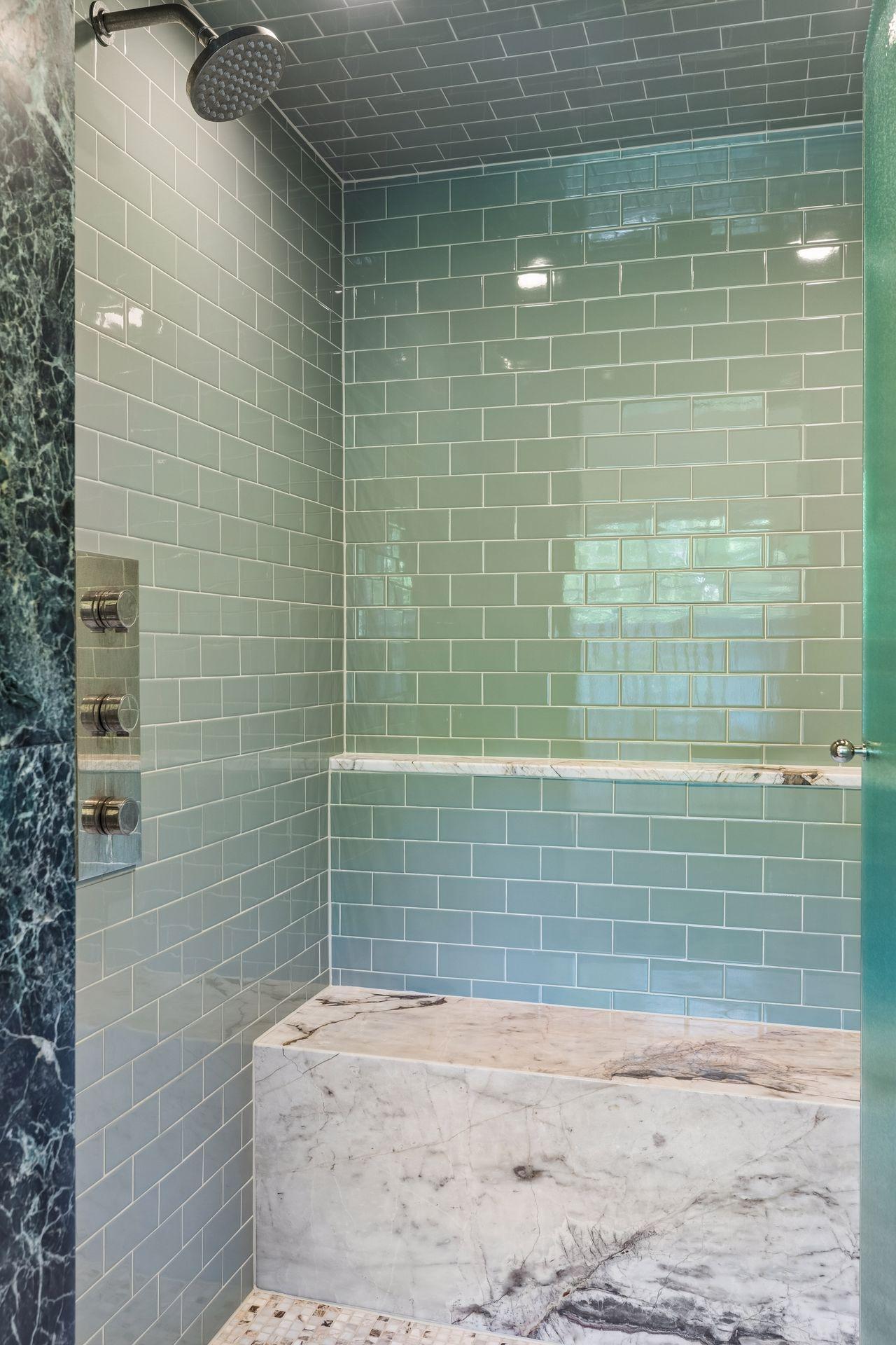 Spacious steam shower with marble bench and floor to ceiling tile.