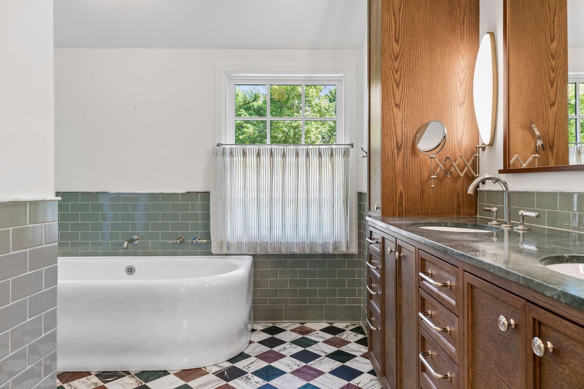 The renovated primary bath was designed with the finest details in mind: dual vanities with luxury fixtures, marble tile and counters, custom cabinetry with integrated outlets, designer lighting, and charming privacy curtains...
