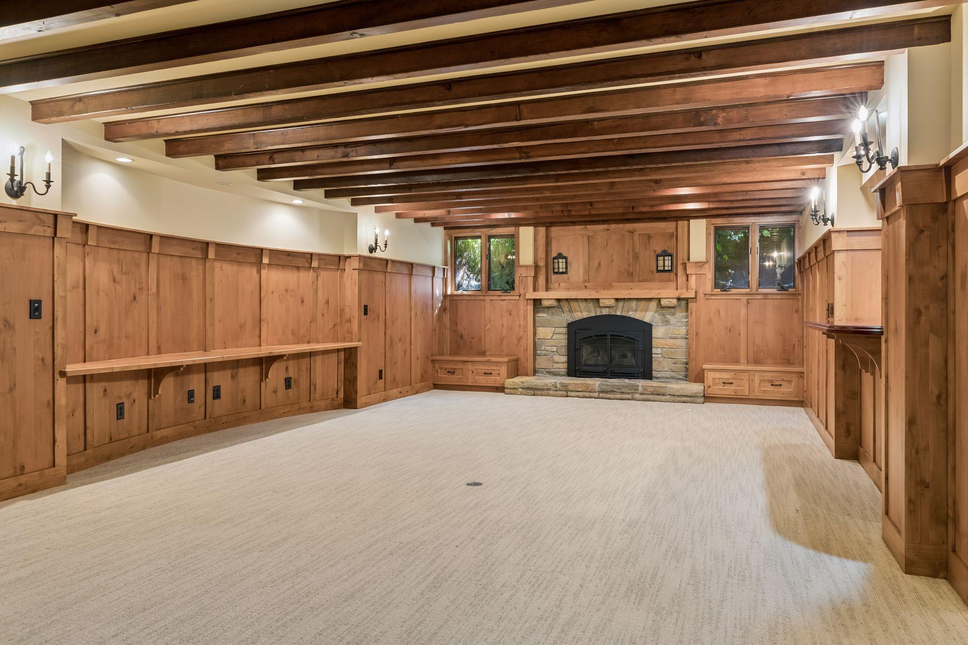 The lower level recreation room features wood beams and paneling, a gas fireplace, wet bar and kitchenette.