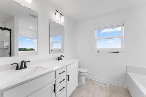 A glass-enclosed shower and nearby soaking tub provide daily escapes in the ownerâs bathroom