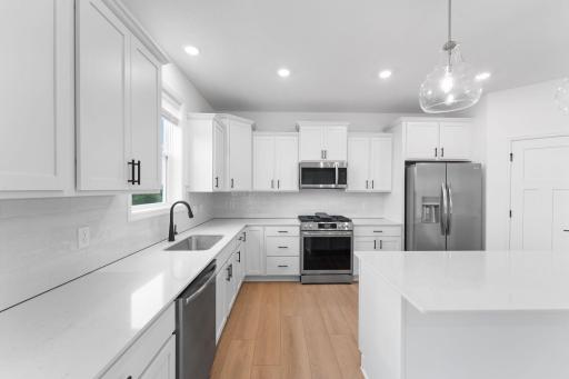 This stylish and multifunctional kitchen comes complete with brand-new stainless steel appliances, sleek quartz countertops and Shaker-style cabinetry.