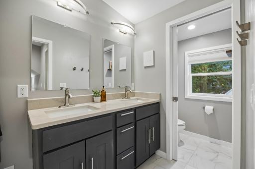 Beautiful private ensuite bath with tiled floors and a dual-sink vanity.