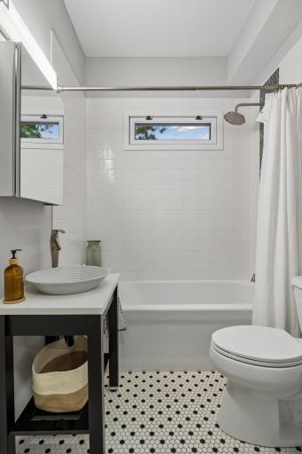 Main-floor full bath featuring elegant hexagon tile flooring and a beautifully tiled shower.