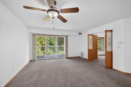 Living/dining room with french doors leading to second bedroom. Patio doors face east. Wooded lot is out back.
