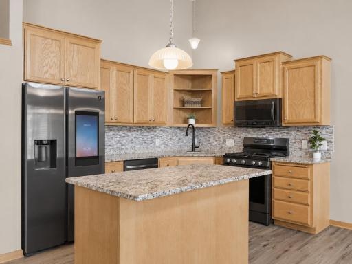 The heart of the home, this open-concept kitchen offers granite countertops, stainless steel appliances, a smart refrigerator, and a spacious island that's perfect for gathering, entertaining, or casual meals.