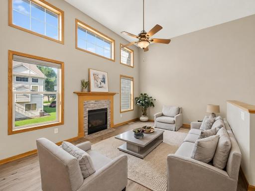 VIRTUAL STAGING! The dramatic two-story living room is filled with natural light from soaring windows and features a cozy gas fireplace with a classic mantel, plus plenty of space for large-scale furniture.