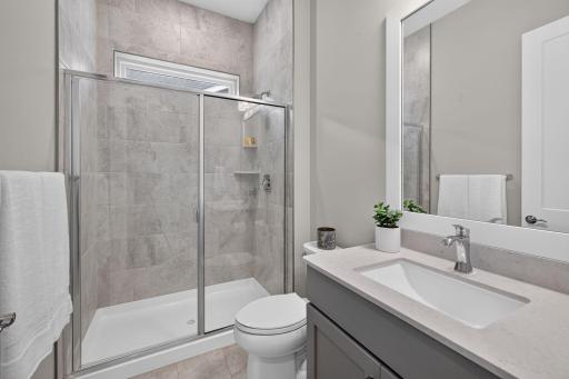 Guest bath features a walk-in tiled shower and clean, contemporary finishes