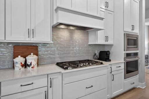 A gas cooktop, wall oven and stylish tile backsplash complete the well-appointed kitchen