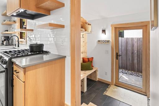 Transition from outdoors to in with ease - the fully tiled mudroom boasts vaulted ceilings and custom built-ins