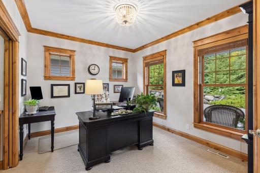 A flexible main-floor office with beautiful wood trim and windows overlooking the surrounding greenery.