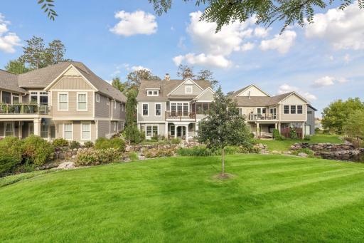A broad lawn and creekside setting create a sense of openness behind the home.