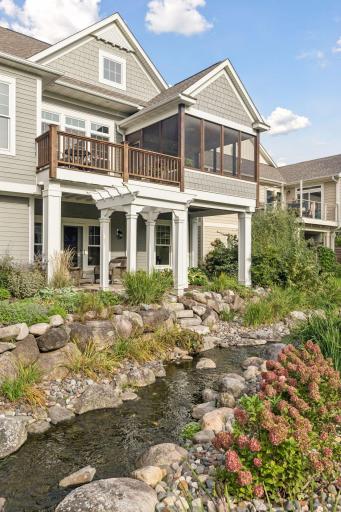 The covered patio feels connected to the surrounding gardens, lawn, and creek.
