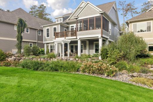 The screen porch and upper deck sit above beautifully established landscaping.