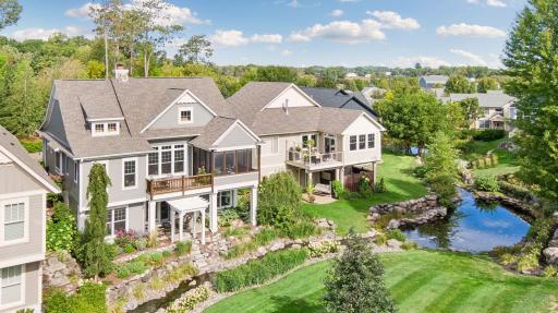 Aerial perspective highlights the deck, screen porch, gardens, and winding creek below.