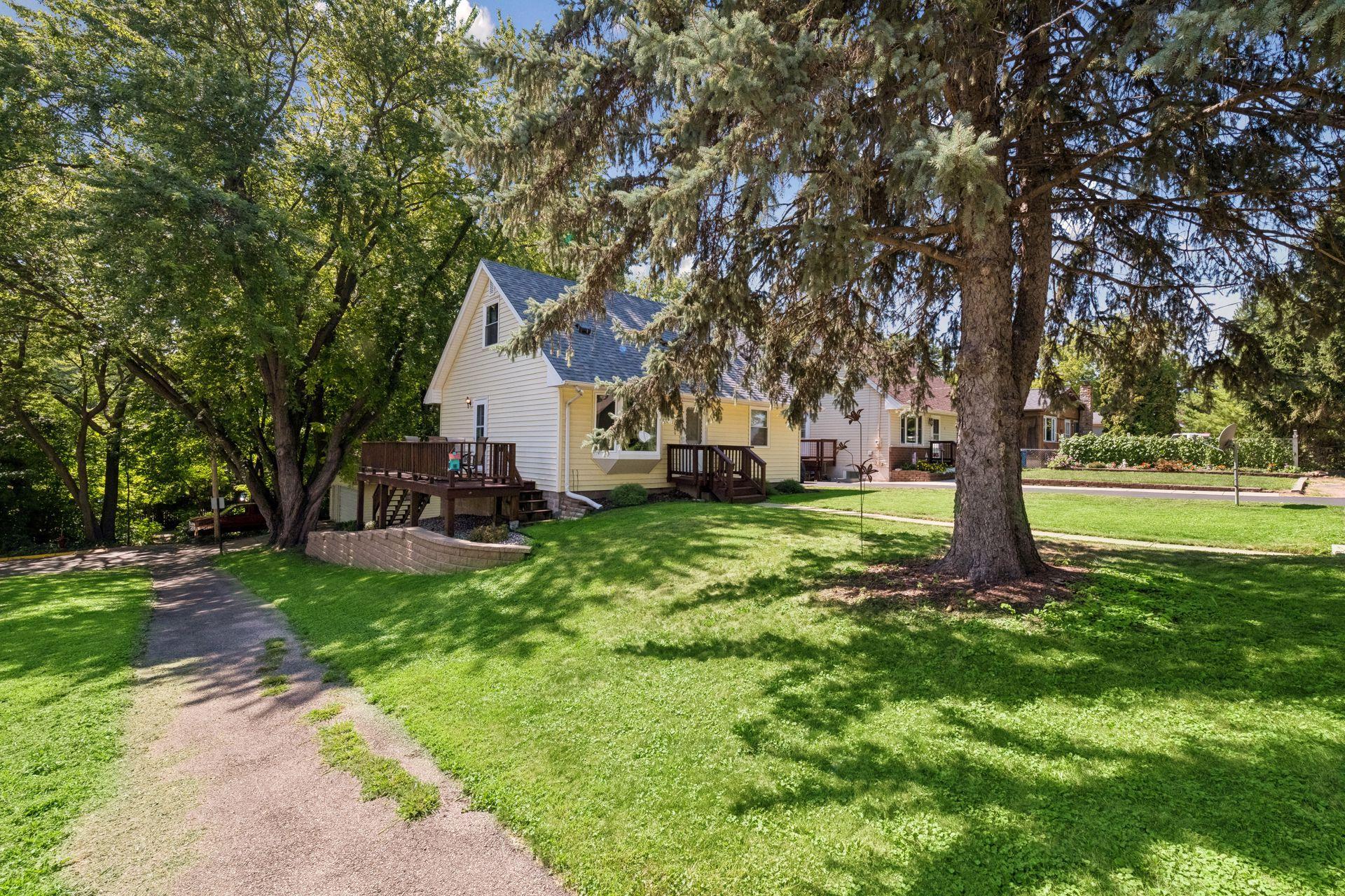 Side of home offers deck and ample tree coverage