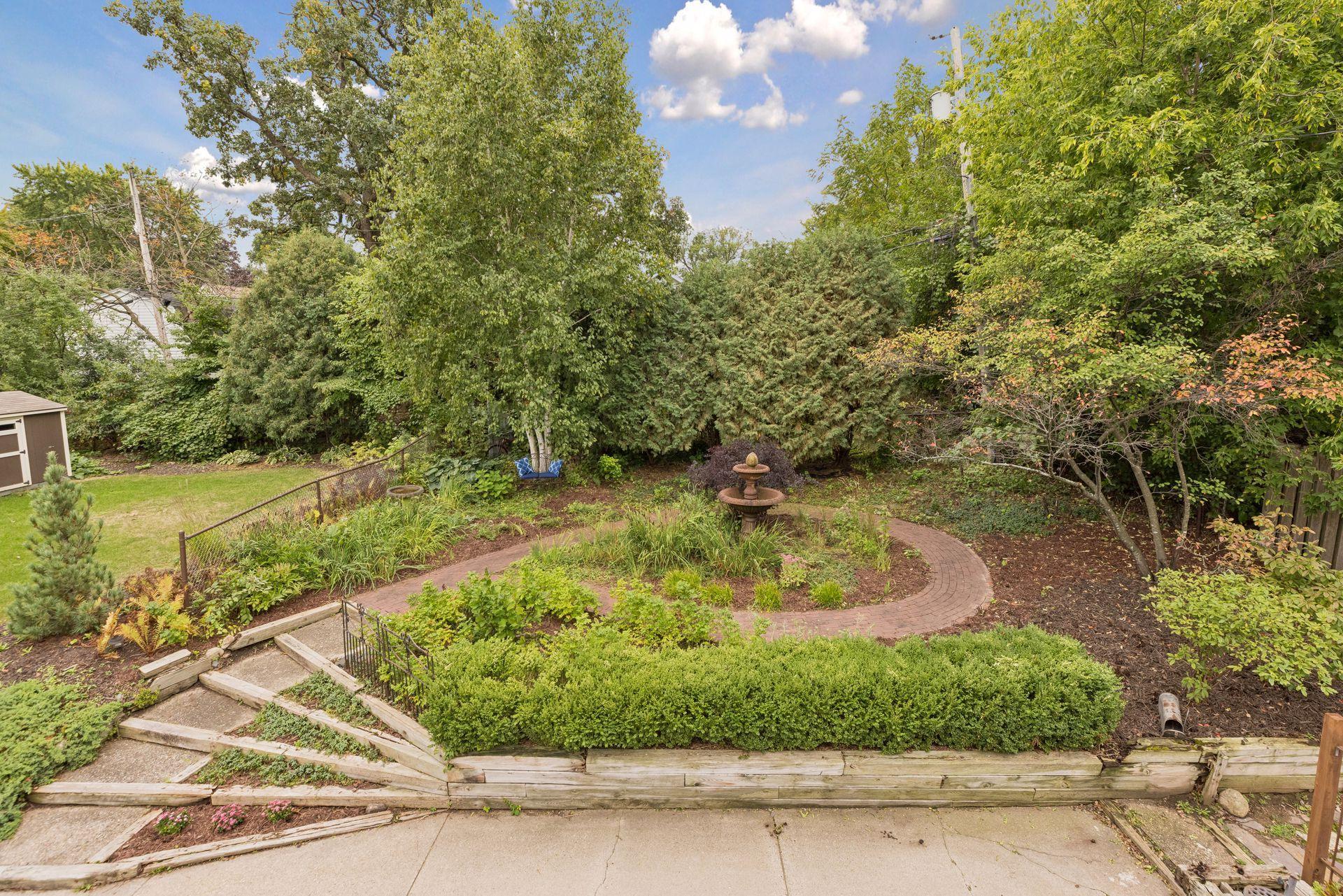 Backyard overlooks this beautiful perennial garden featuring rose bushes, magnolia, boxwoods, phlox, ferns, vinca vines, grasses and so many more.