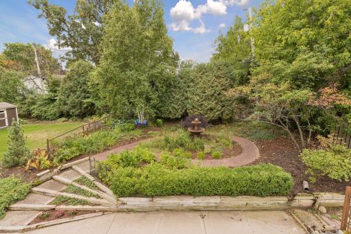 Backyard overlooks this beautiful perennial garden featuring rose bushes, magnolia, boxwoods, phlox, ferns, vinca vines, grasses and so many more.