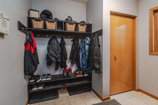 The large mud room has a closet, hooks for hanging and a bright window.