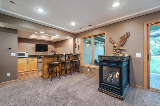 The family room includes a 3-sided gas fireplace, a recreation space with a maple bar with granite countertops, and additional storage cabinetry.