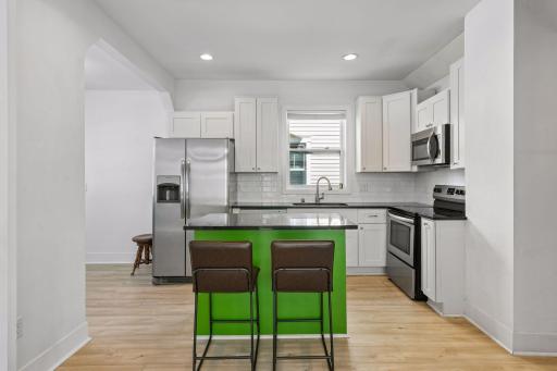 Crisp, clean and modern kitchen with center island - with a bold touch of color, granite counters, subway tile backsplash, and stainless appliances. NEW Pergo LVP flooring in 2025.