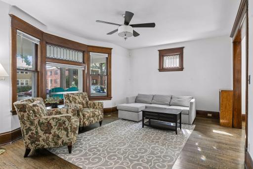Bright and airy living room with original natural woodwork, leaded windows, and gleaming hardwood floors.