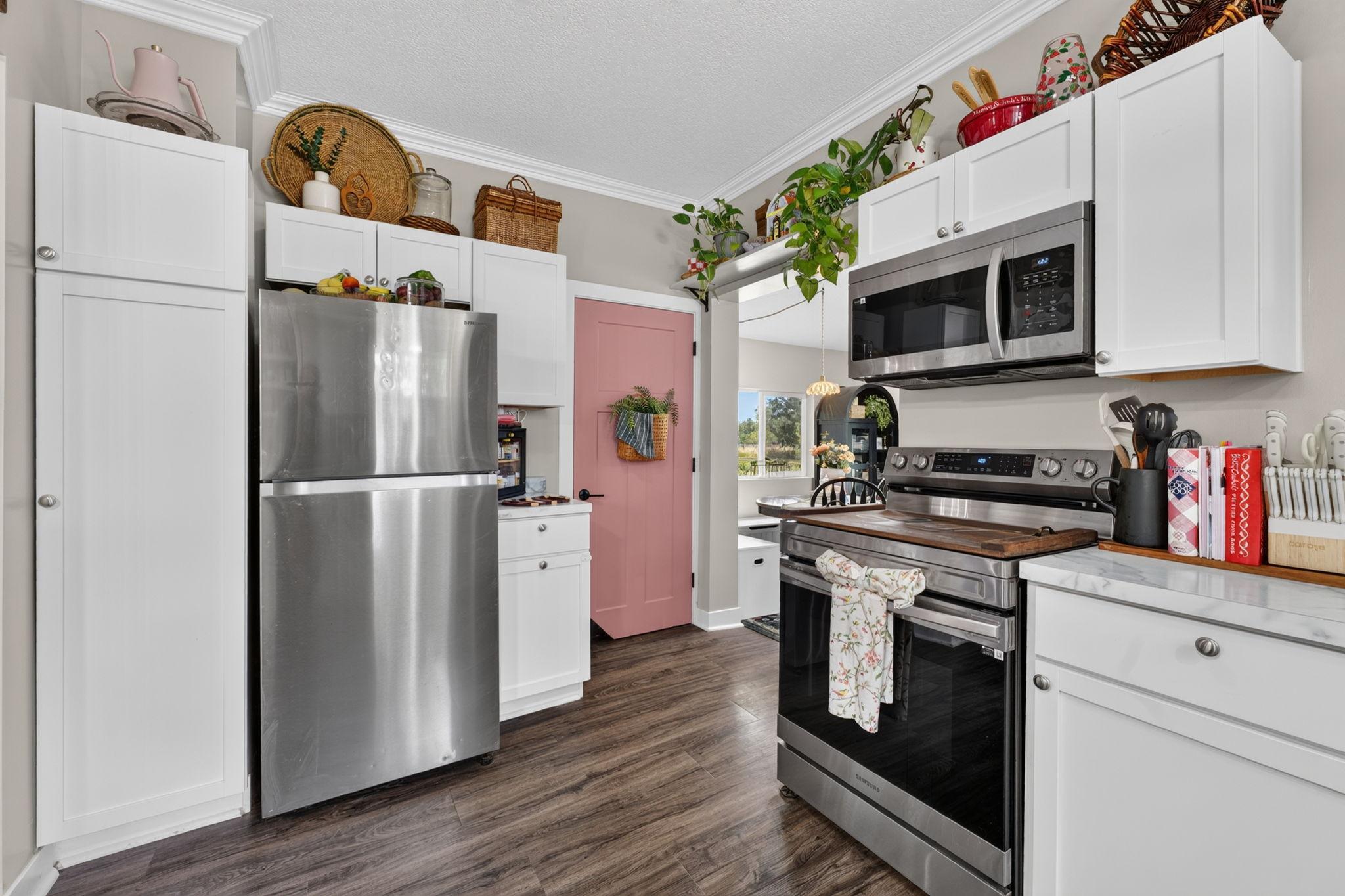 Inviting kitchen with white cabinetry, stainless steel appliances, and a pop of personality with the charming basement door.