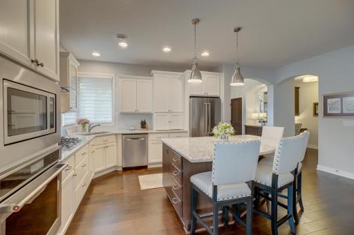 The gourmet kitchen showcases Cambria countertops, stainless steel appliances, a sleek backsplash, and generous prep space.