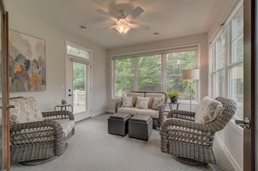 French doors lead to an inviting sunroom with access to the deck, patio, and tree-lined backyard.