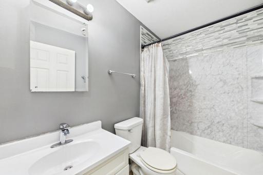 Full bath with stone vanity counter and updated bath surround - Upper unit 2